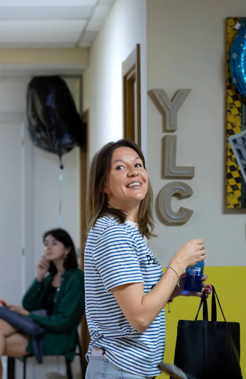 A student in a striped top smiling by the YLC letters