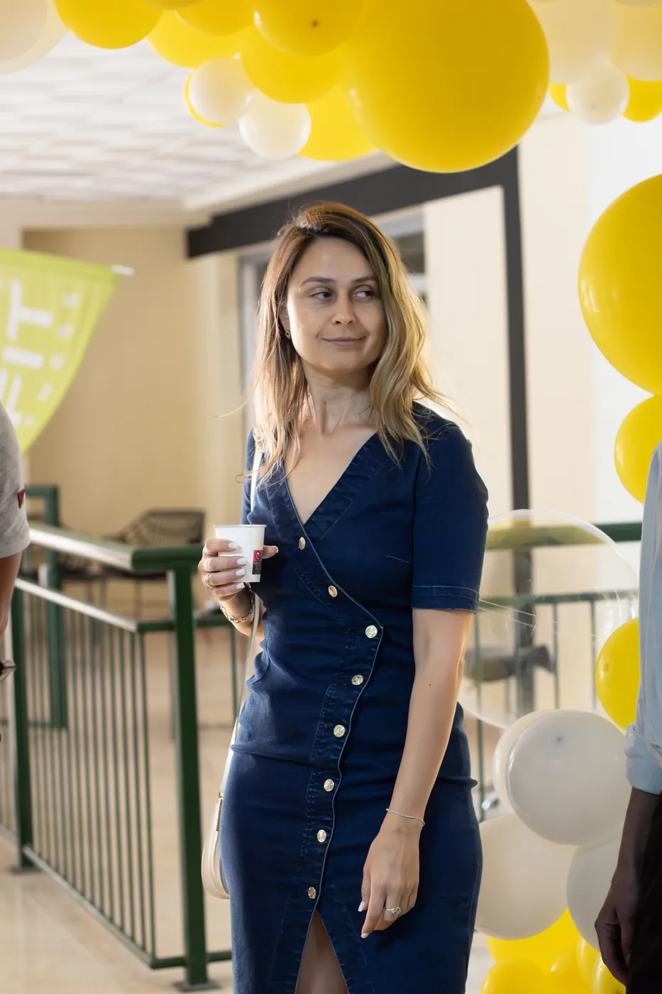 A student in a blue dress with a drink at the school party