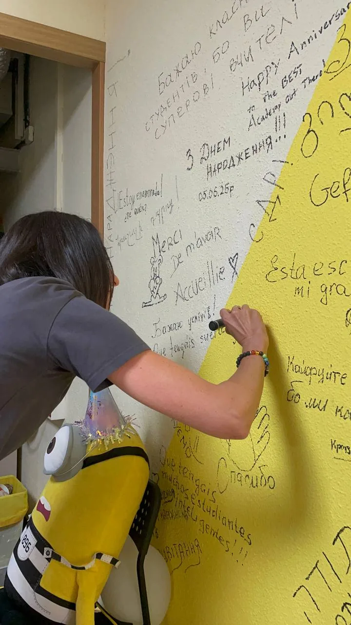 A student writing on the wishes wall next to the yellow minion