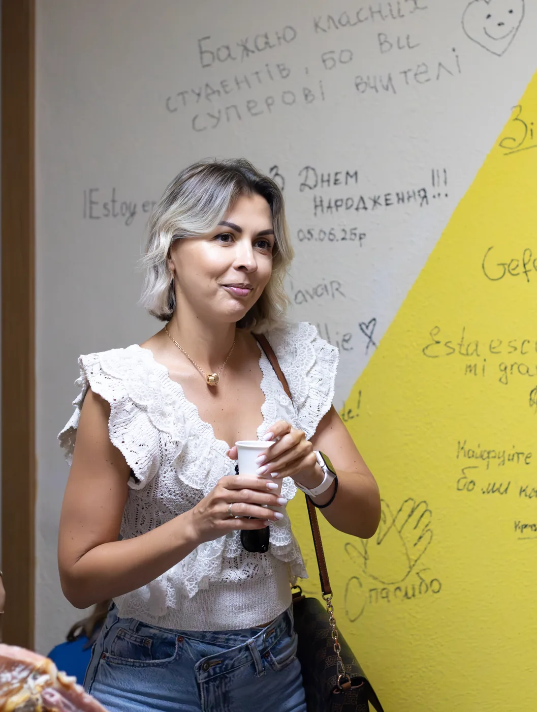 A student posing by the yellow wall covered in handwritten greetings