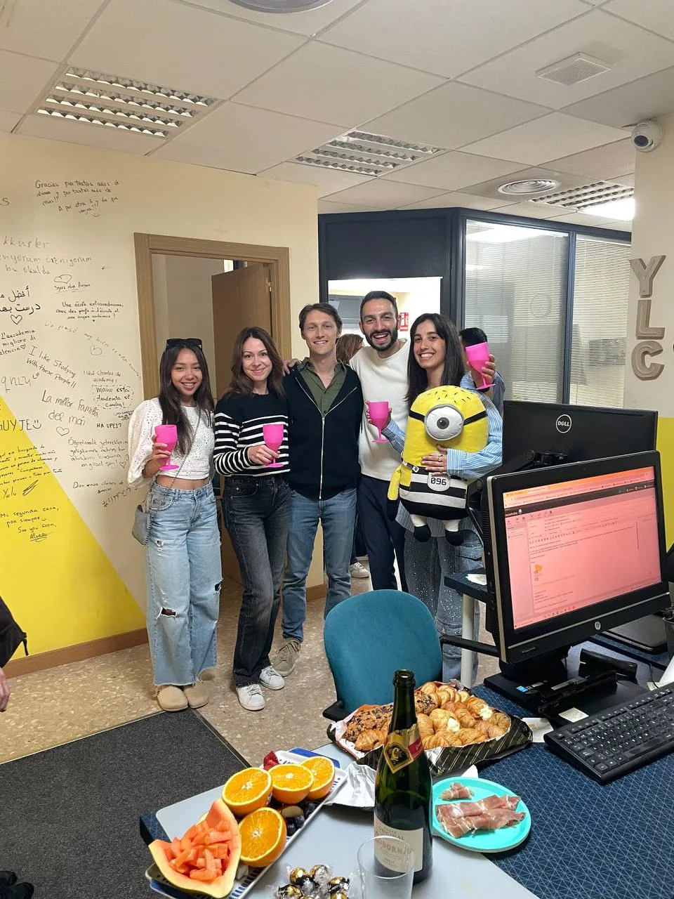 Students toasting with pink cups next to the minion in the office