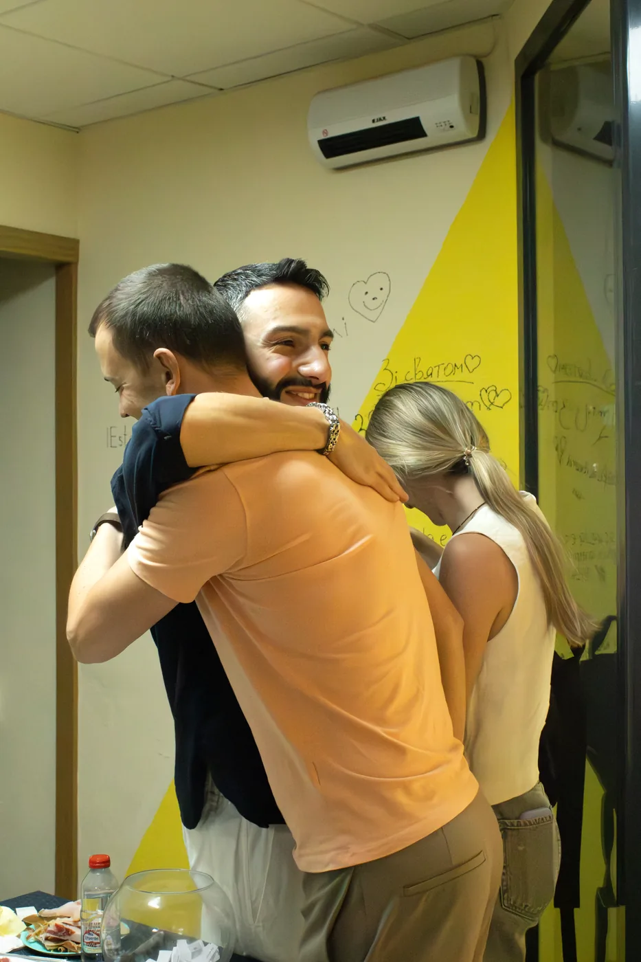 Students and teachers hugging by the yellow wishes wall
