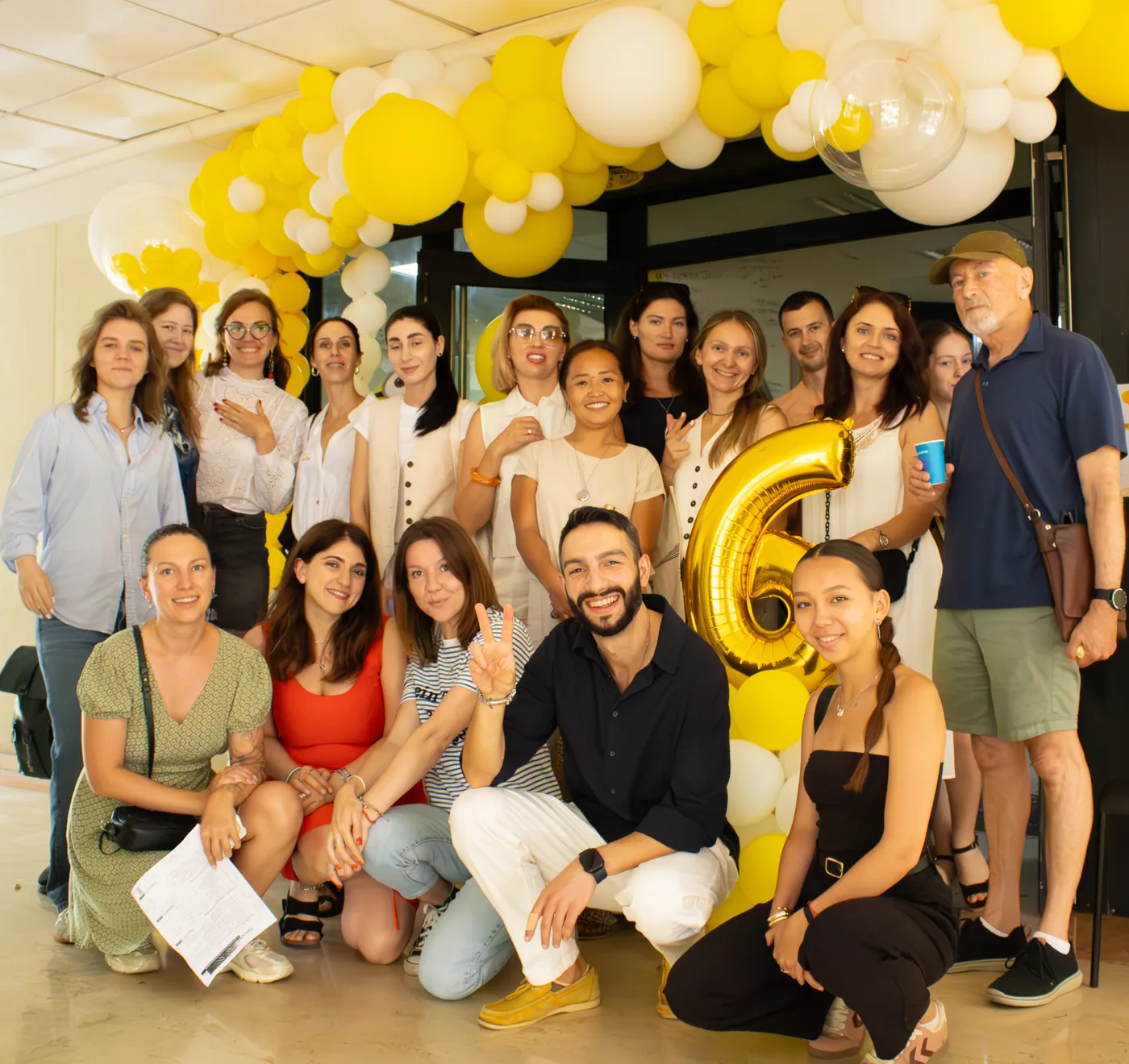 Group photo of students and teachers with the golden sixth-anniversary balloon
