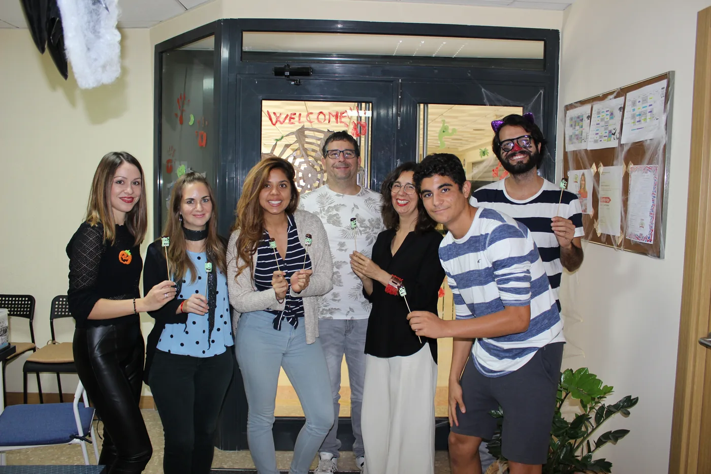 A group of students with lollipops at the Halloween-decorated entrance