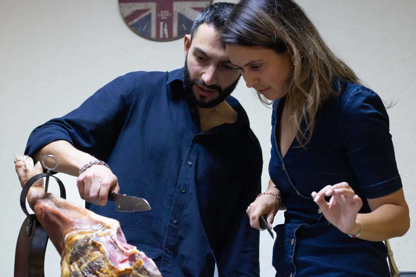 A teacher showing a student how to carve jamón