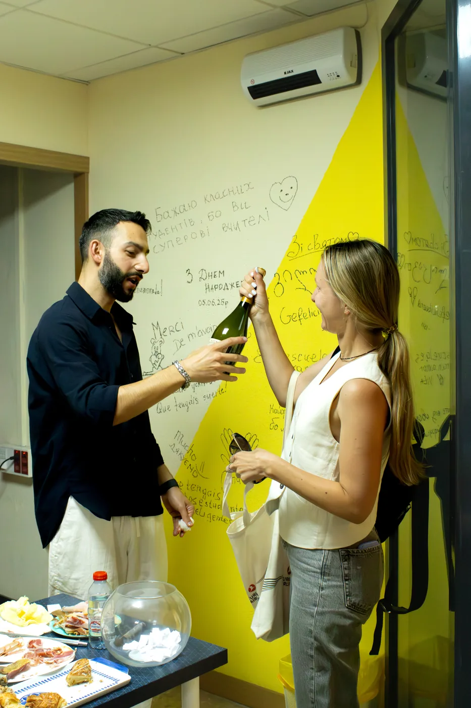 A teacher and a student opening a bottle of cava for the toast