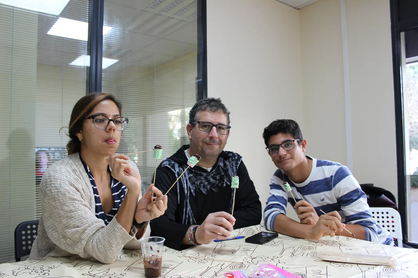 Three students with Halloween sweets at the classroom table